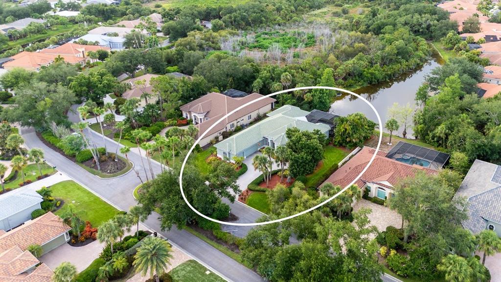 An aerial view shows a single-story house with a green roof surrounded by lush landscaping — 24 GRAND PALMS BOULEVARD, ENGLEWOOD, FL