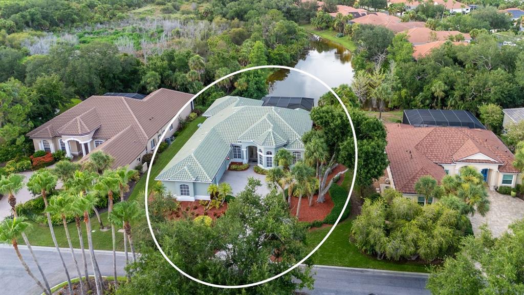 An aerial view of a light-colored house with a green tile roof and pool cage — 24 GRAND PALMS BOULEVARD, ENGLEWOOD, FL