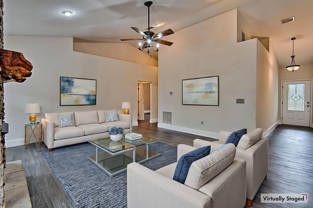 A living room features a vaulted ceiling, a ceiling fan, a sofa, and two armchairs — 9880 NW 110TH STREET, CHIEFLAND, FL