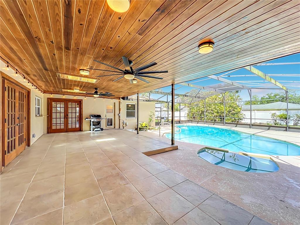 A covered patio with a wood-paneled ceiling overlooks a screened-in swimming pool and spa — 105 CEDAR OAK TRAIL, LONGWOOD, FL