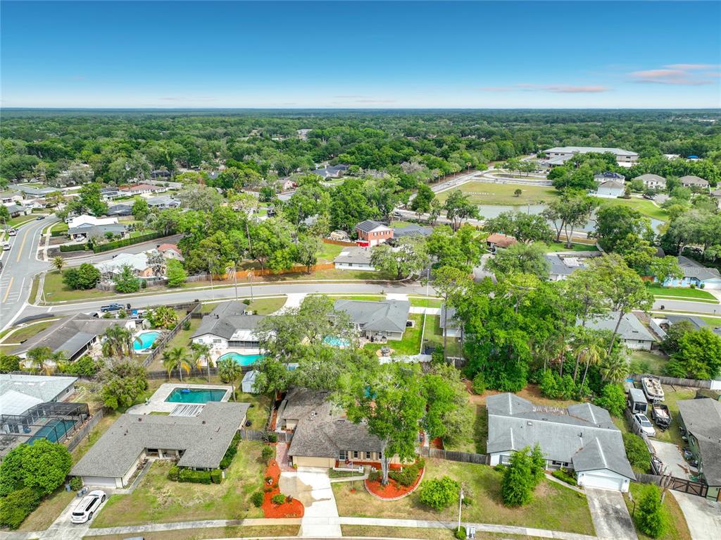 An aerial view shows a suburban neighborhood with single-family homes, swimming pools, and mature trees — 105 CEDAR OAK TRAIL, LONGWOOD, FL