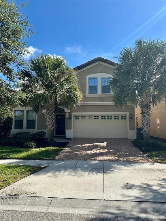 A two-story house with a beige exterior, a two-car garage, and two palm trees — 1941 NICE COURT, KISSIMMEE, FL
