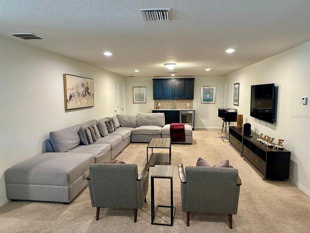 A finished basement features a large sectional sofa, two armchairs, a wet bar, and television — 1941 NICE COURT, KISSIMMEE, FL