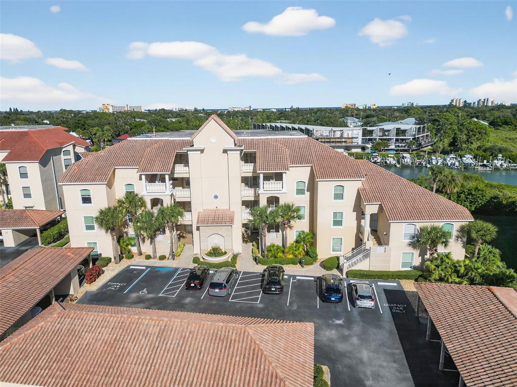 An aerial view of a multi-story apartment building with a parking lot and waterfront — 434 BOUCHELLE DRIVE UNIT 304, NEW SMYRNA BEACH, FL