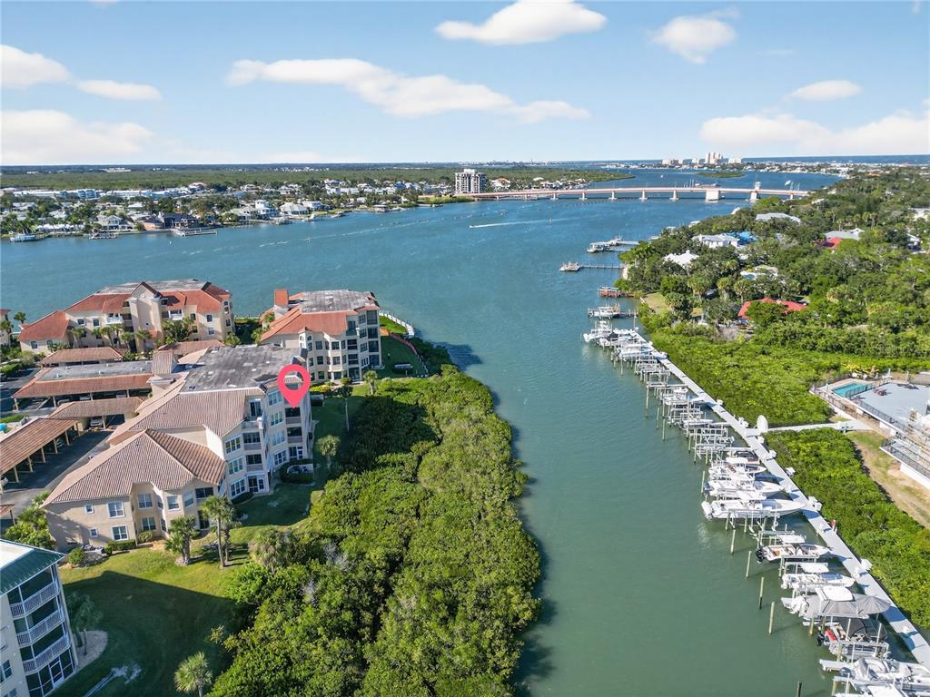 An aerial view shows waterfront condominium buildings, a marina with docked boats, and a bridge — 434 BOUCHELLE DRIVE UNIT 304, NEW SMYRNA BEACH, FL
