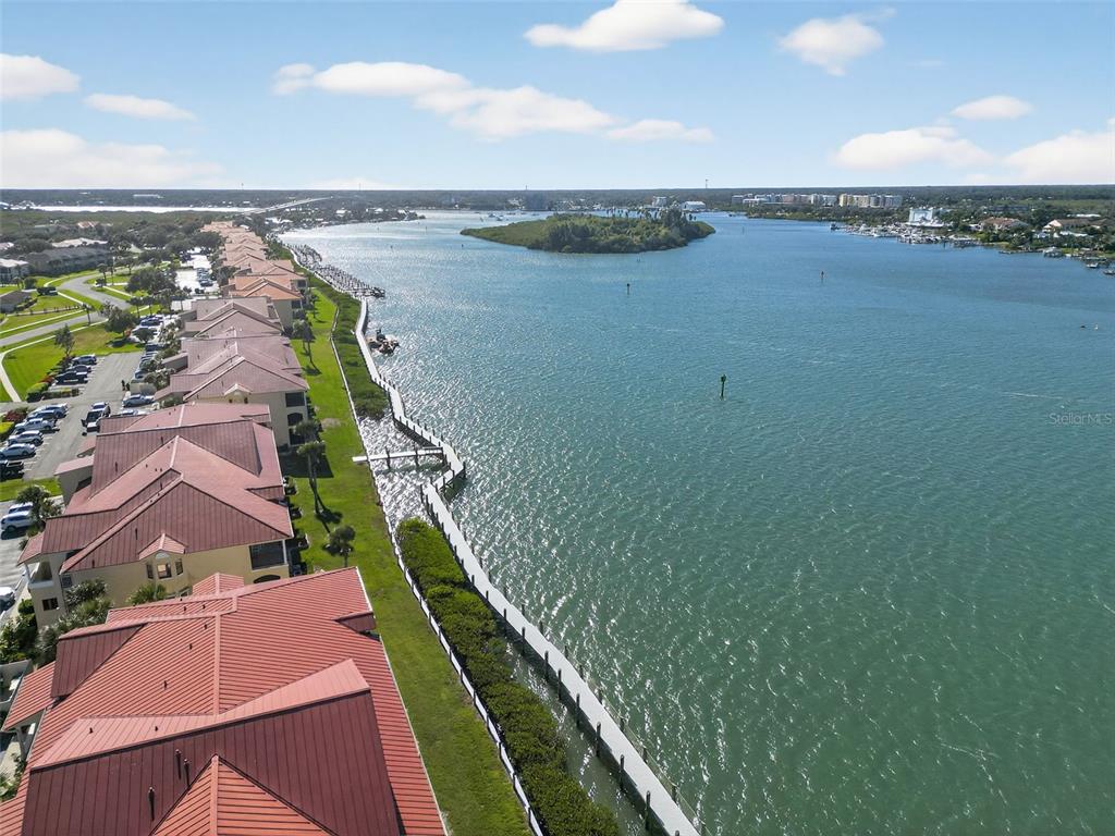 An aerial view shows a row of waterfront condominiums with red roofs along a bay — 434 BOUCHELLE DRIVE UNIT 304, NEW SMYRNA BEACH, FL