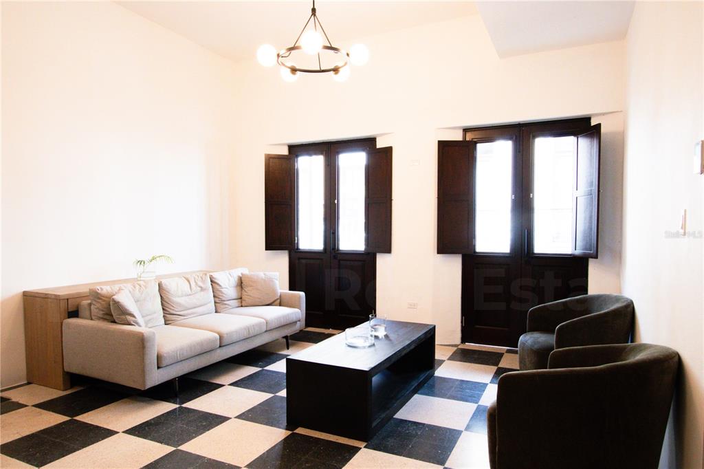 A living room features a checkered floor, a light-colored sofa, two dark armchairs, and shutters — 254-256 SAN FRANCISCO STREET UNIT 202, SAN JUAN, PR