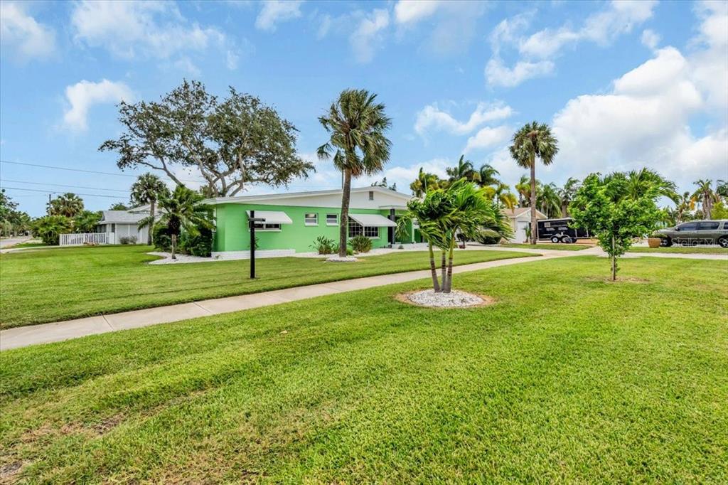 A bright green, single-story house sits on a large, grassy lot with several palm trees — 3002 58TH STREET S, GULFPORT, FL