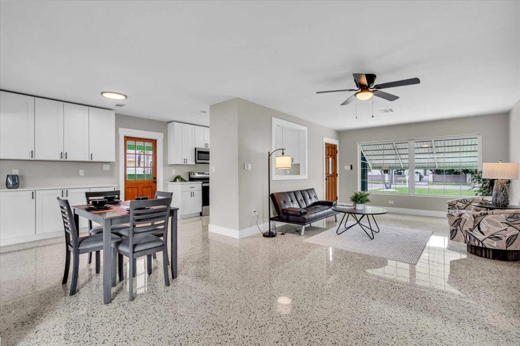An open-concept living and dining area features white cabinetry, a dark dining set, and terrazzo flooring — 3002 58TH STREET S, GULFPORT, FL
