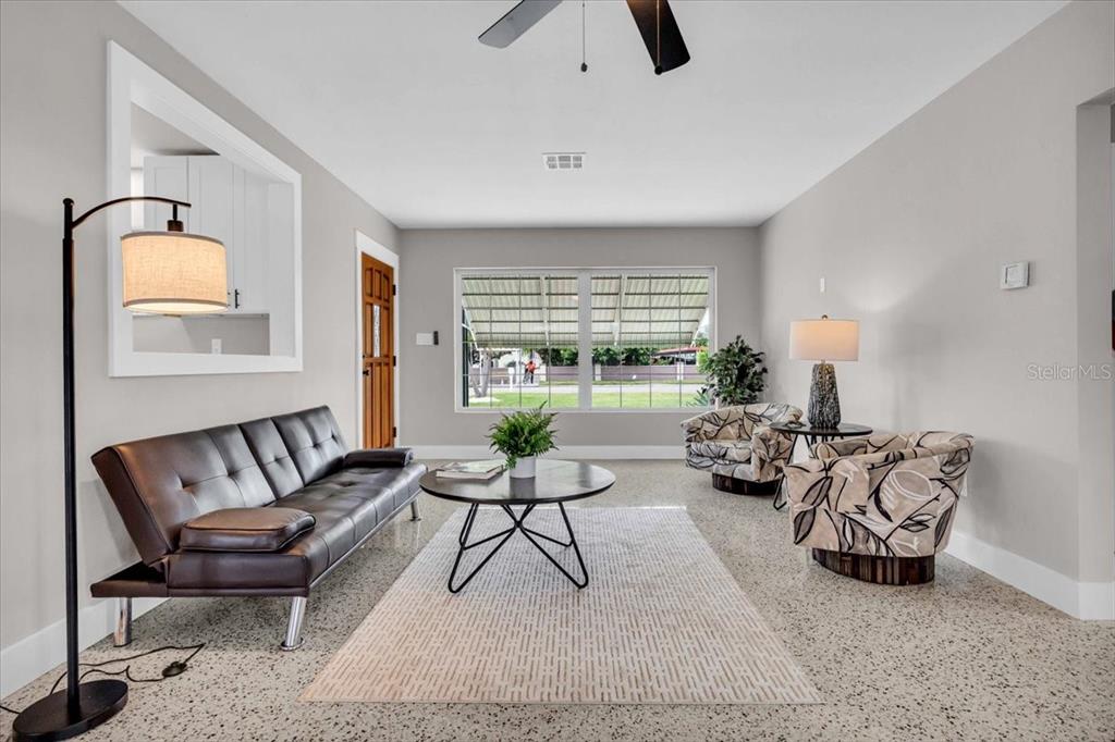 A living room features a dark leather sofa, two patterned armchairs, and terrazzo flooring — 3002 58TH STREET S, GULFPORT, FL