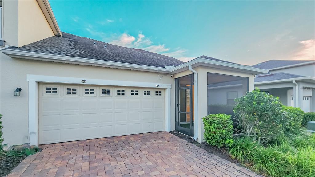 A beige house exterior features a two-car garage and a screened-in porch area — 2945 CELLO LANE, KISSIMMEE, FL