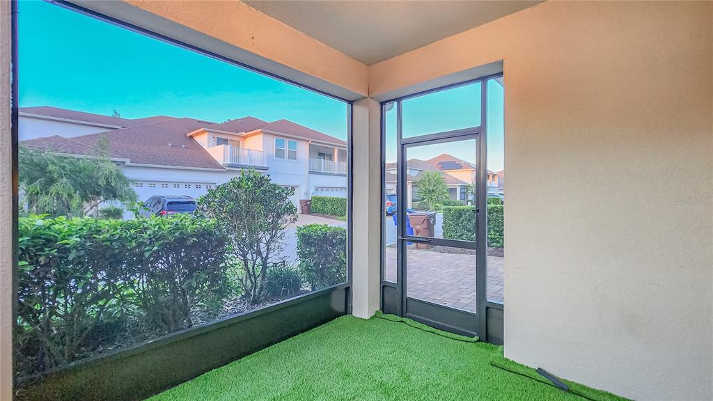 A screened-in patio with artificial turf flooring and a view of neighboring houses — 2945 CELLO LANE, KISSIMMEE, FL