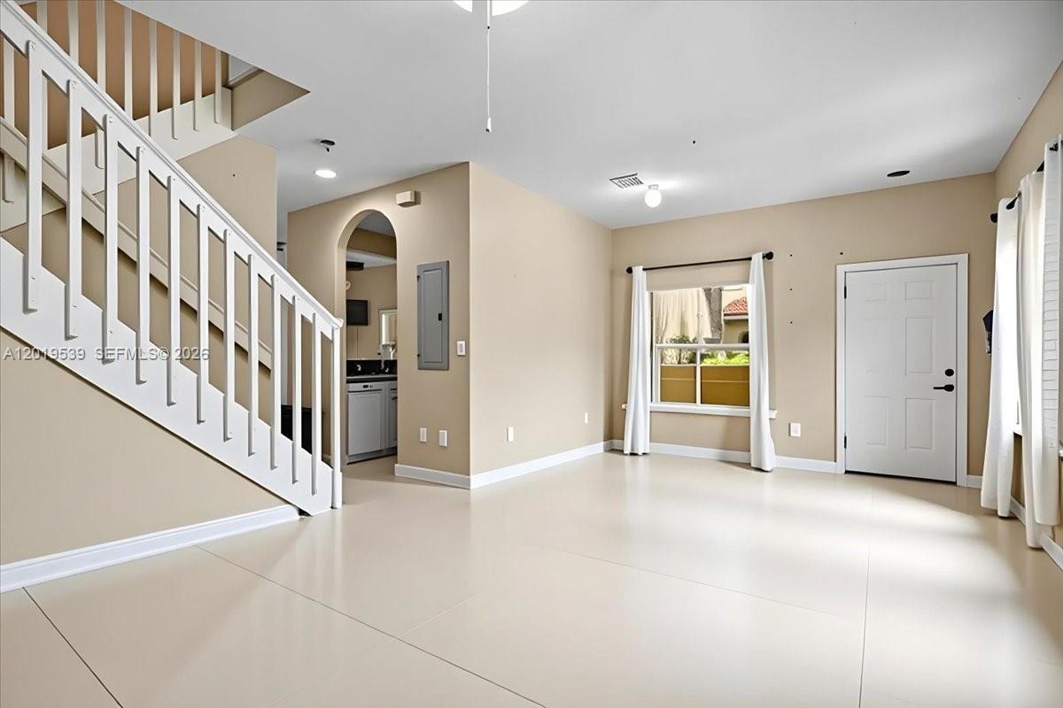 An empty living room features white tile floors, a staircase, and a doorway to a kitchen — 3417 Merrick Ct # 1206, Margate FL 33063, MARGATE, FL
