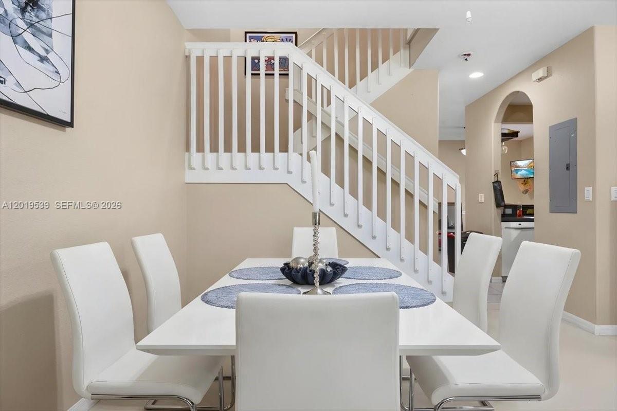 A dining area features a white table and chairs positioned in front of a staircase — 3417 Merrick Ct # 1206, Margate FL 33063, MARGATE, FL