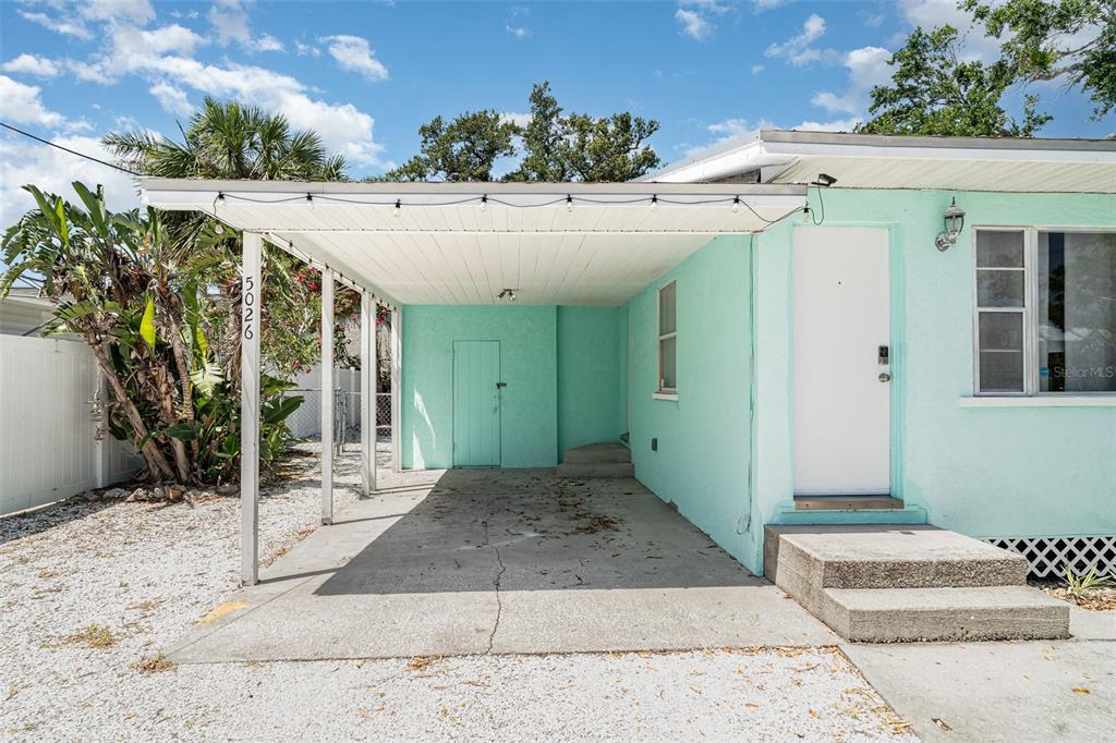 A light green house exterior features a covered carport with string lights and a concrete driveway — 5026 CALLE MINORGA, SARASOTA, FL