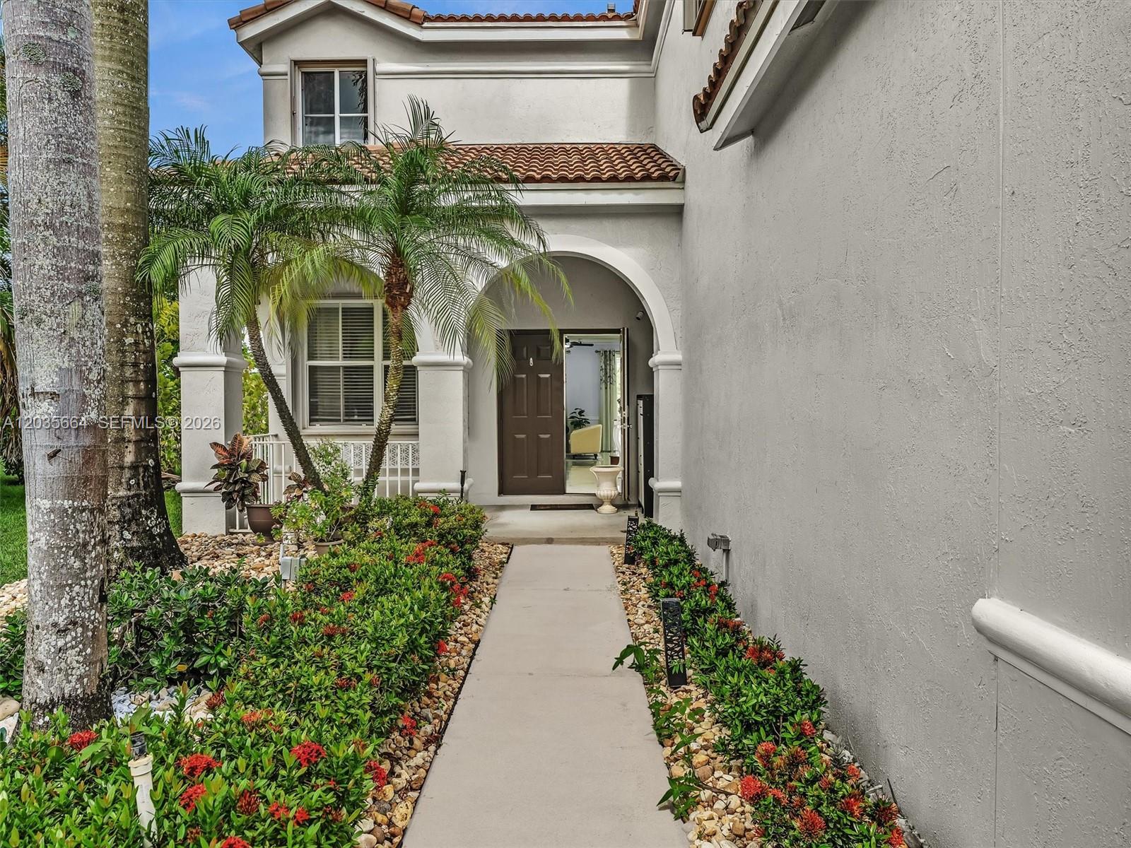 A concrete walkway leads to the arched entryway of a two-story stucco home — 1581 Winterberry Ln, Weston FL 33327, WESTON, FL
