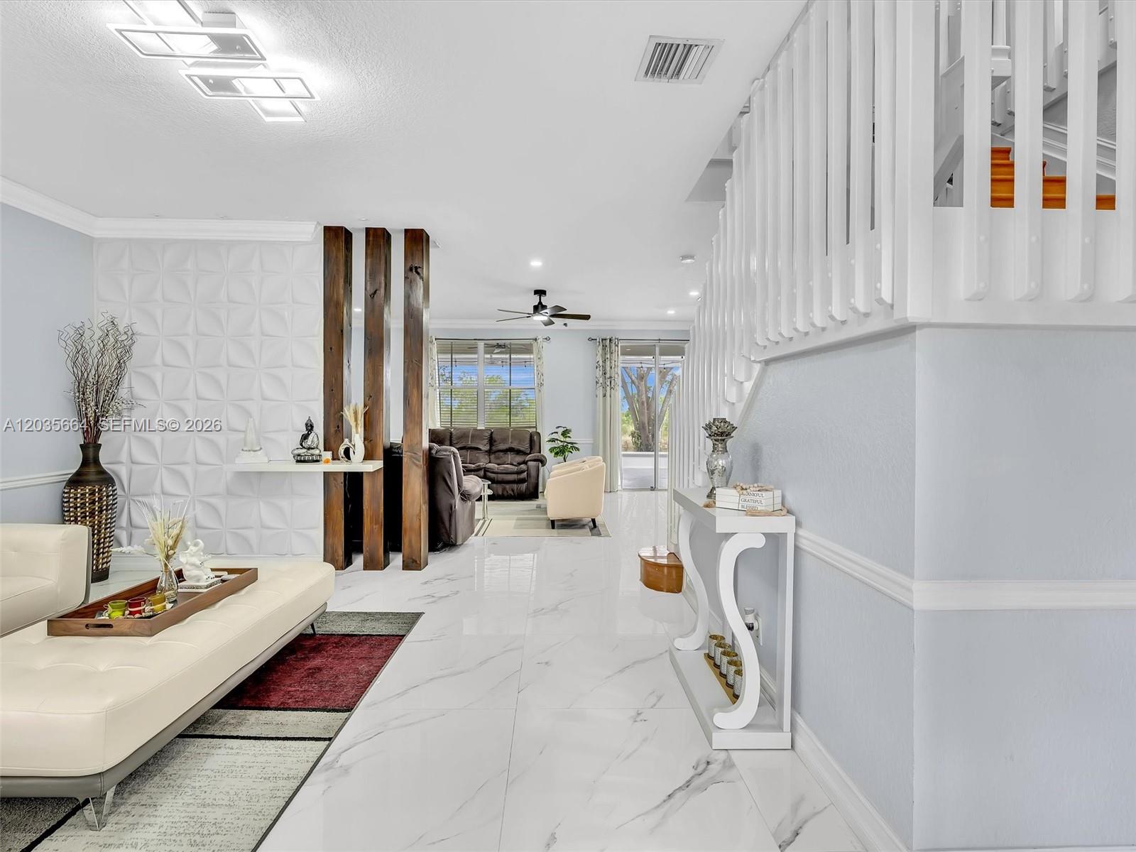 A living room features white marble floors, a textured accent wall, and a wooden staircase — 1581 Winterberry Ln, Weston FL 33327, WESTON, FL