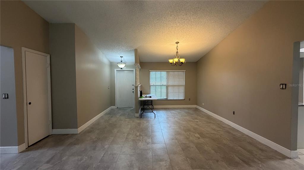 A room with light-colored tile flooring, beige walls, a vaulted ceiling, and a dining area — 6434 ROCKINGTREE LANE, ORLANDO, FL