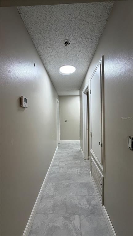 A narrow hallway features light gray tile flooring, a textured ceiling, and a circular light fixture — 6434 ROCKINGTREE LANE, ORLANDO, FL