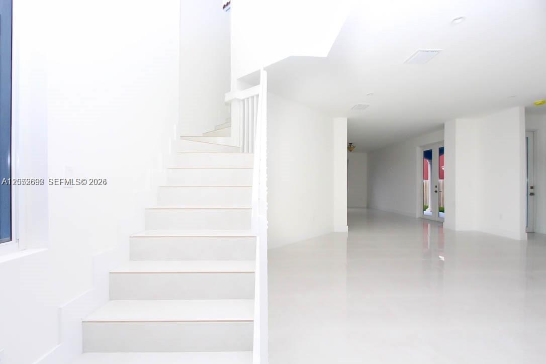 A white staircase leads upward in a bright, minimalist room with polished tile flooring — 15631 SW 11th Ter, Miami FL 33194, MIAMI, FL