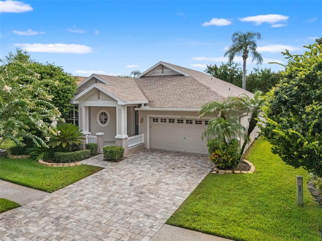 A single-story house with a paved driveway, a two-car garage, and a covered front porch — 19425 MELODY FAIR PLACE, LUTZ, FL