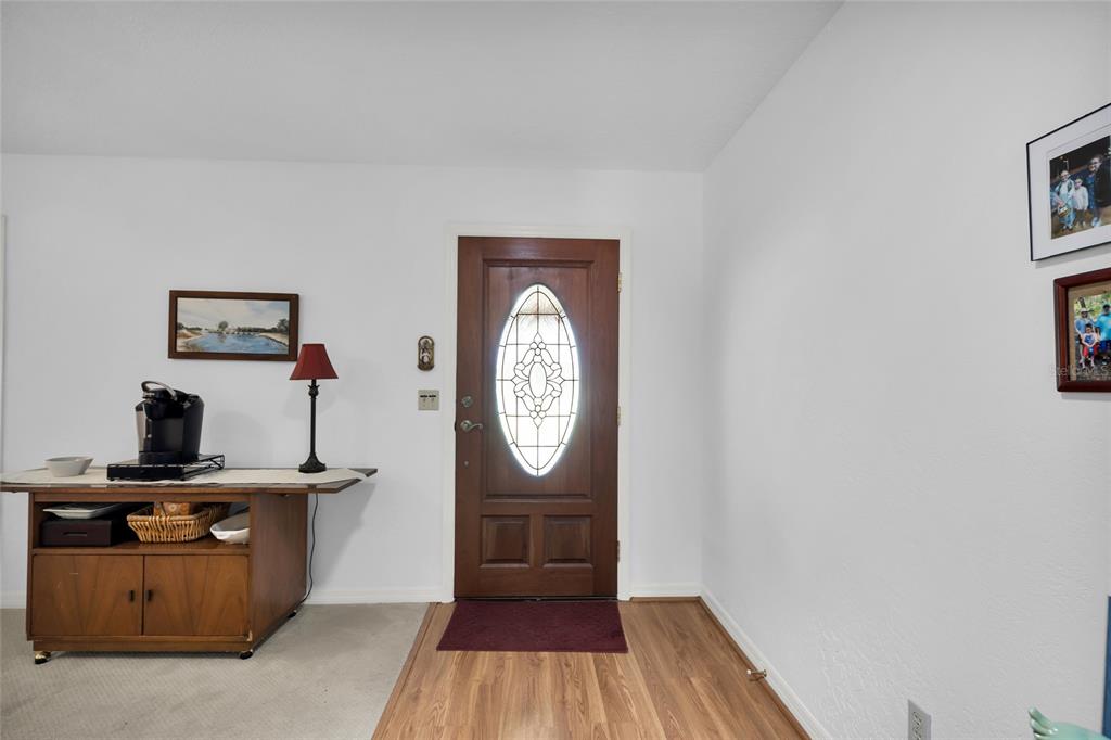 An entryway features a wood front door with a decorative oval glass insert and flooring — 2045 SE 32ND STREET, OCALA, FL