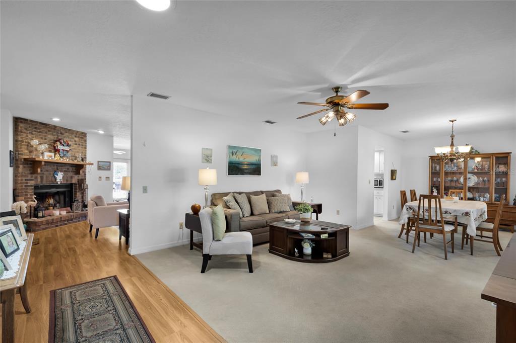 A living room and dining area with carpet, a brick fireplace, and a ceiling fan — 2045 SE 32ND STREET, OCALA, FL