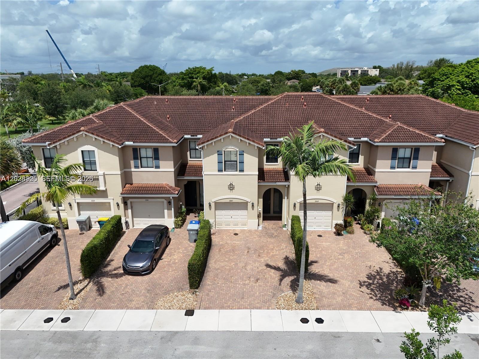 An aerial view shows a row of multi-story townhomes with tiled roofs and paved driveways — 3345 NW 11th Ave, Pompano Beach FL 33064, POMPANO BEACH, FL