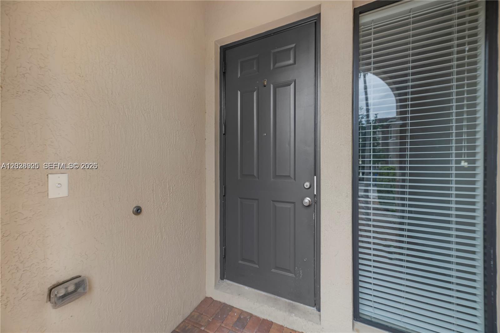 A dark gray front door is positioned next to a window with closed blinds — 3345 NW 11th Ave, Pompano Beach FL 33064, POMPANO BEACH, FL