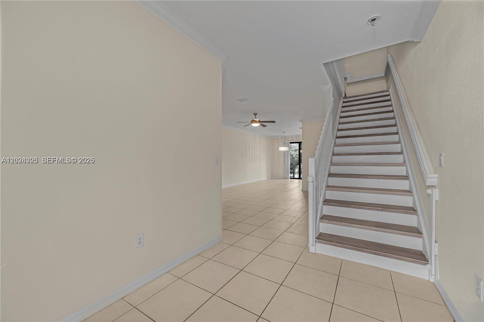 A staircase with white railings and wood-toned treads sits beside an open-concept tiled living area — 3345 NW 11th Ave, Pompano Beach FL 33064, POMPANO BEACH, FL