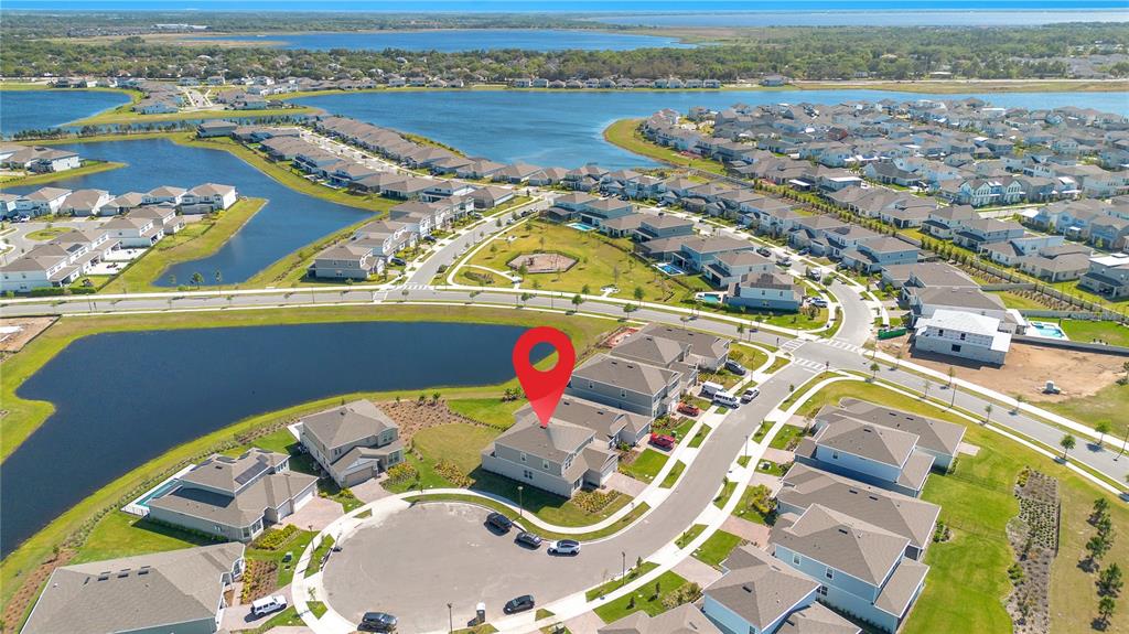 An aerial view shows a suburban neighborhood with houses surrounding a central pond and park — 13231 PANAMA BEACH COURT, ORLANDO, FL