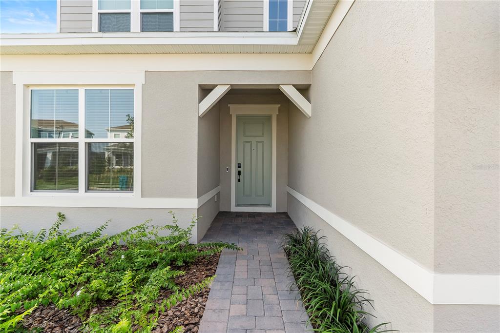 A light green front door is centered under a covered entryway with a brick walkway — 13231 PANAMA BEACH COURT, ORLANDO, FL