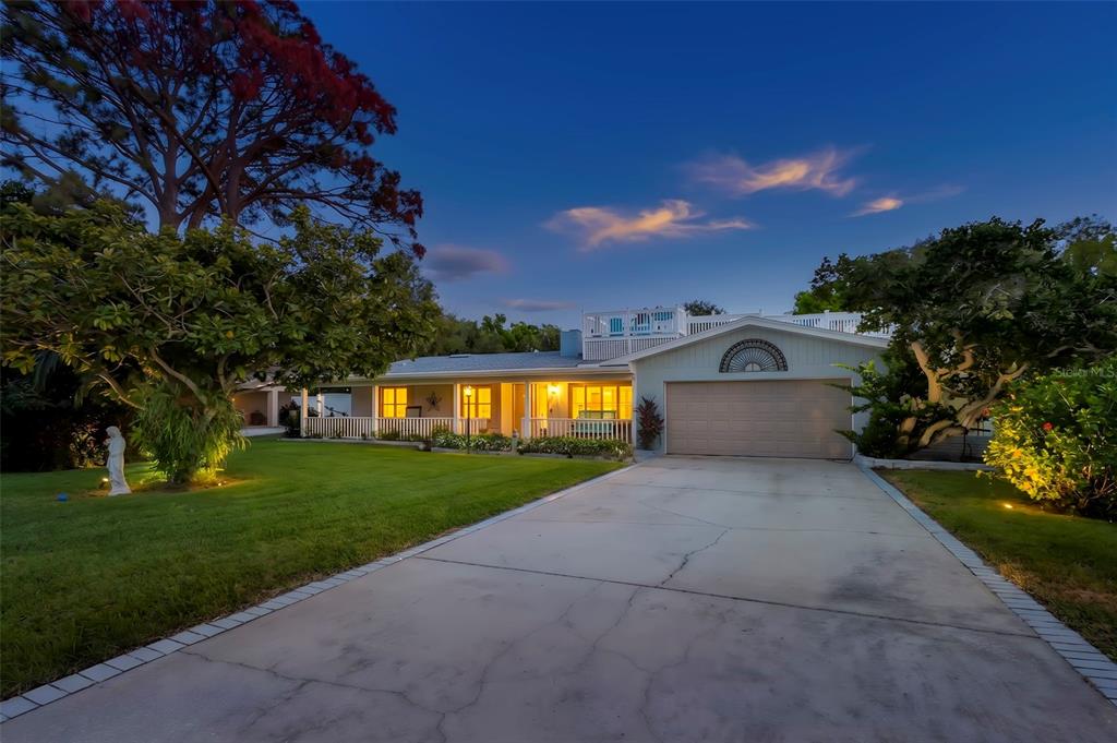 A single-story house with a garage, a front porch, and a rooftop deck at dusk — 121 CARLYLE DRIVE, PALM HARBOR, FL