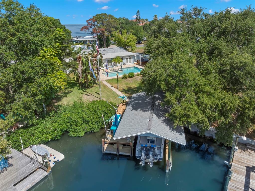 An aerial view shows a waterfront house with a pool, boat dock, and boat lift — 121 CARLYLE DRIVE, PALM HARBOR, FL