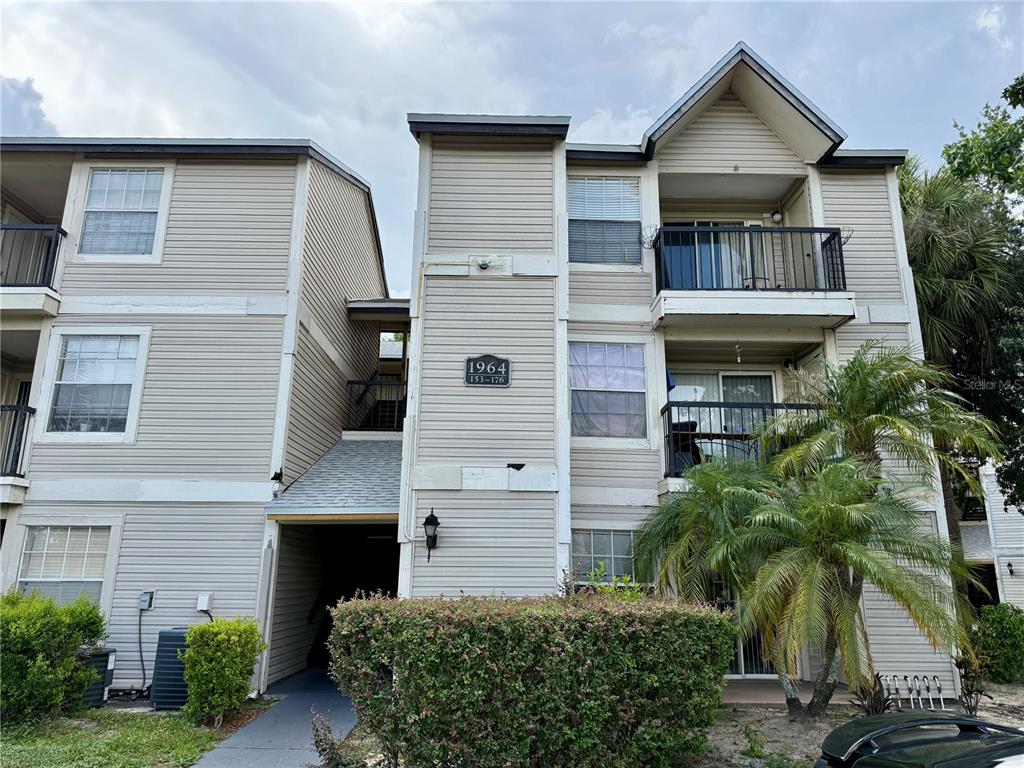 A three-story apartment building exterior features light-colored horizontal siding and private balconies — 1964 LAKE ATRIUMS CIRCLE UNIT 171, ORLANDO, FL