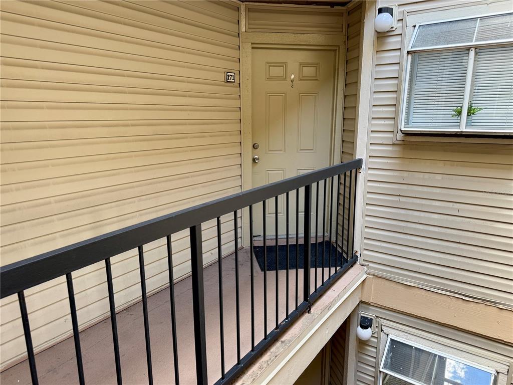 An exterior view of a tan apartment door numbered 171 with a black metal railing — 1964 LAKE ATRIUMS CIRCLE UNIT 171, ORLANDO, FL