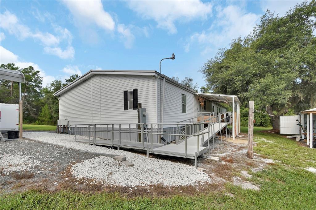 A light gray manufactured home features a metal wheelchair ramp leading to a side entrance — 38846 FOREST DRIVE, EUSTIS, FL