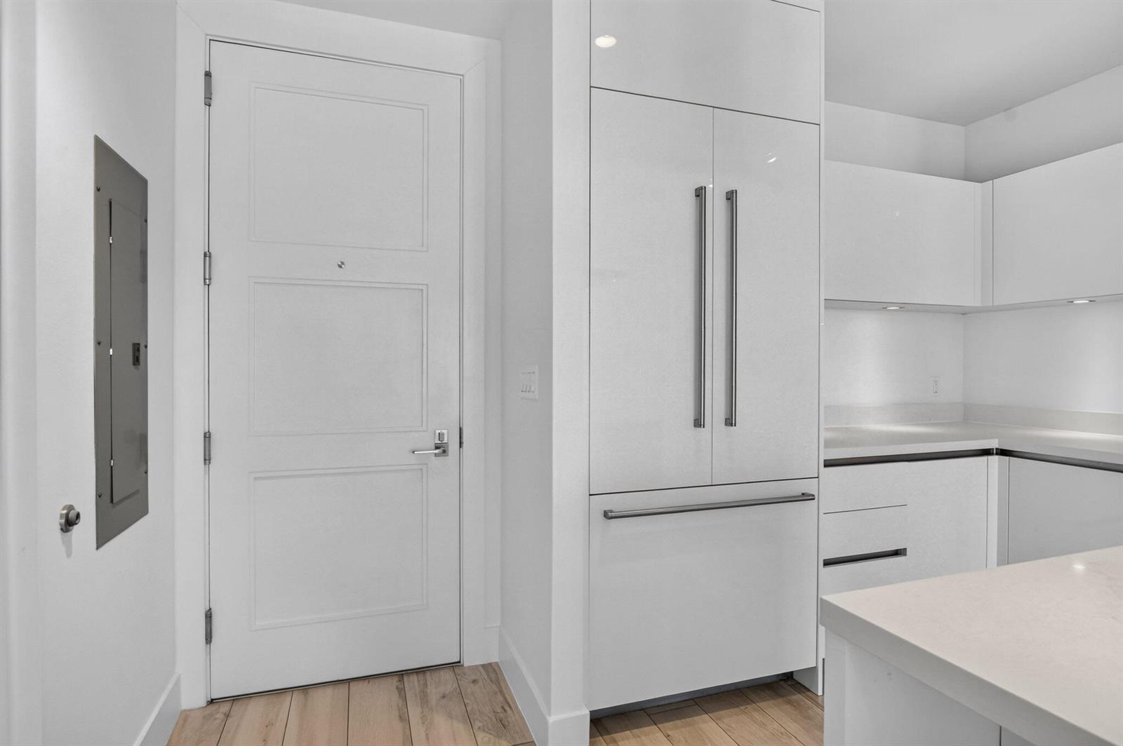 A white kitchen features a panel-ready refrigerator, a paneled door, and light wood flooring — 155 E Boca Raton Road # 1019, Boca Raton FL 33432, BOCA RATON, FL