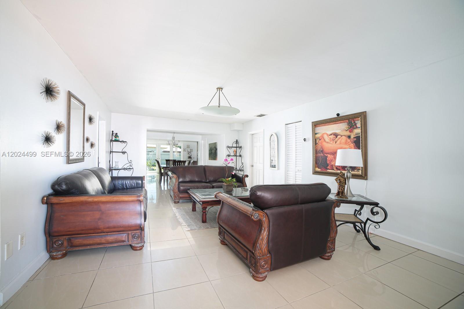 A living room features dark leather furniture, tile flooring, and a large framed painting — 1380 71st St, Miami Beach FL 33141, MIAMI BEACH, FL