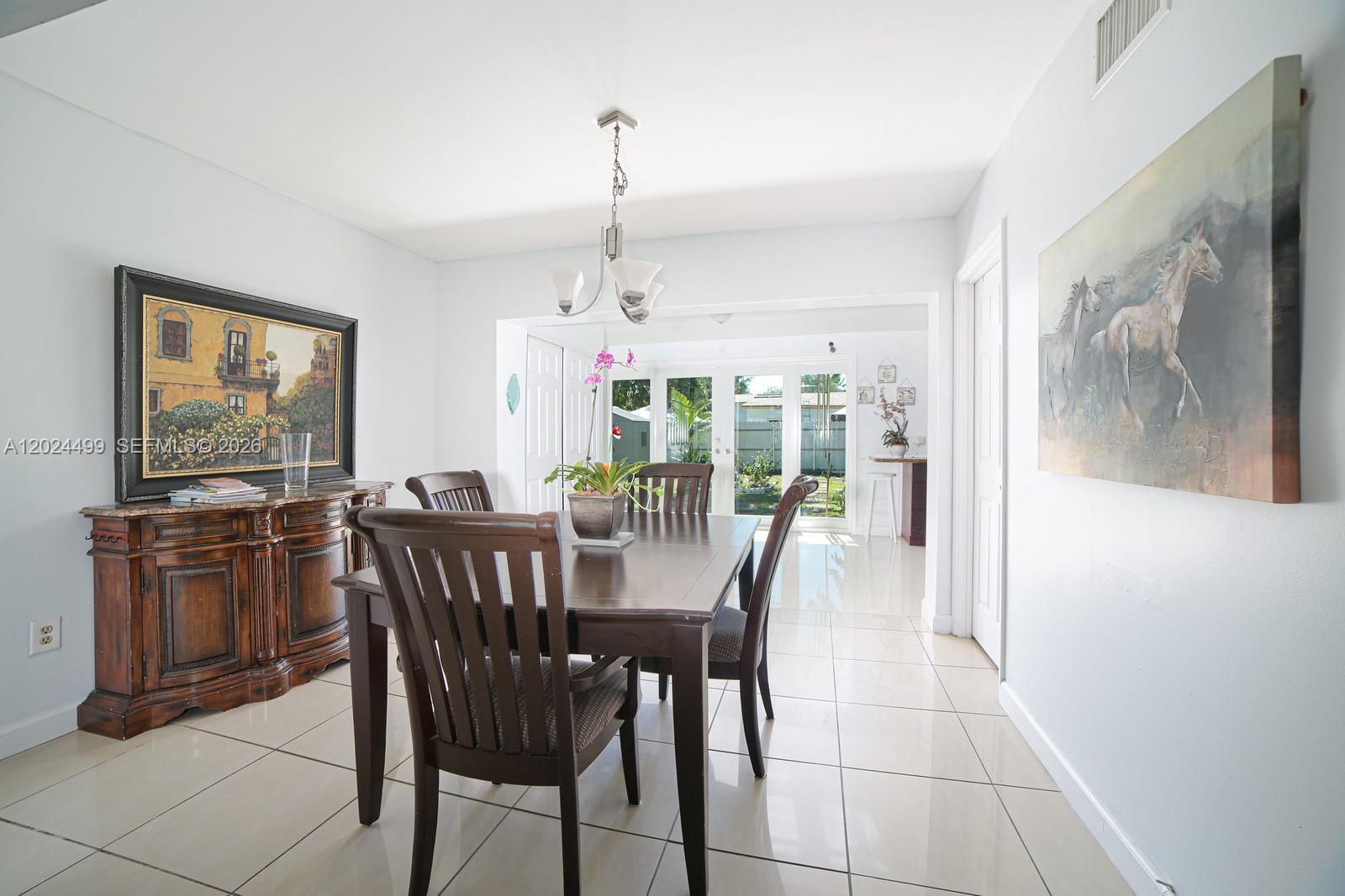 A dining room features a dark wood table and chairs, tile flooring, and two wall paintings — 1380 71st St, Miami Beach FL 33141, MIAMI BEACH, FL
