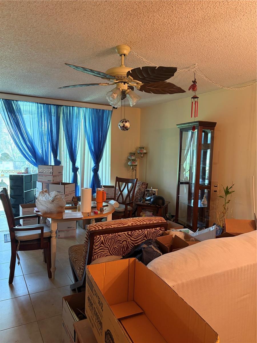 A dining area features a leaf-shaped ceiling fan, blue curtains, and several cardboard moving boxes — 2741 N Pine Island Rd # 109, Sunrise FL 33322, SUNRISE, FL