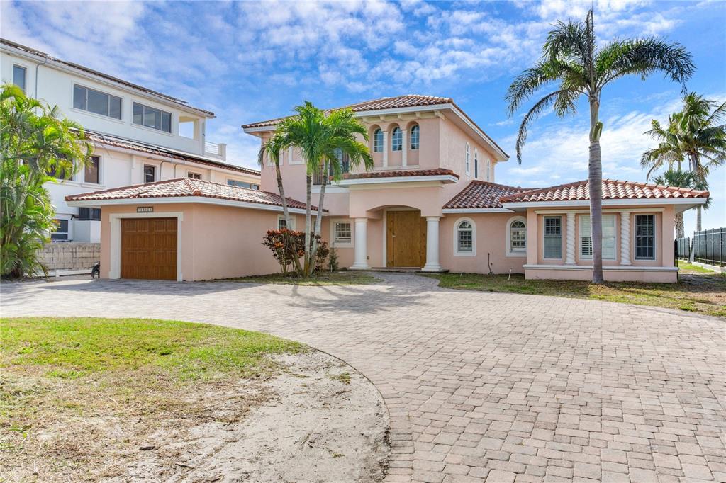 A two-story peach-colored house with a tiled roof and a paved driveway — 16116 GULF BOULEVARD, REDINGTON BEACH, FL