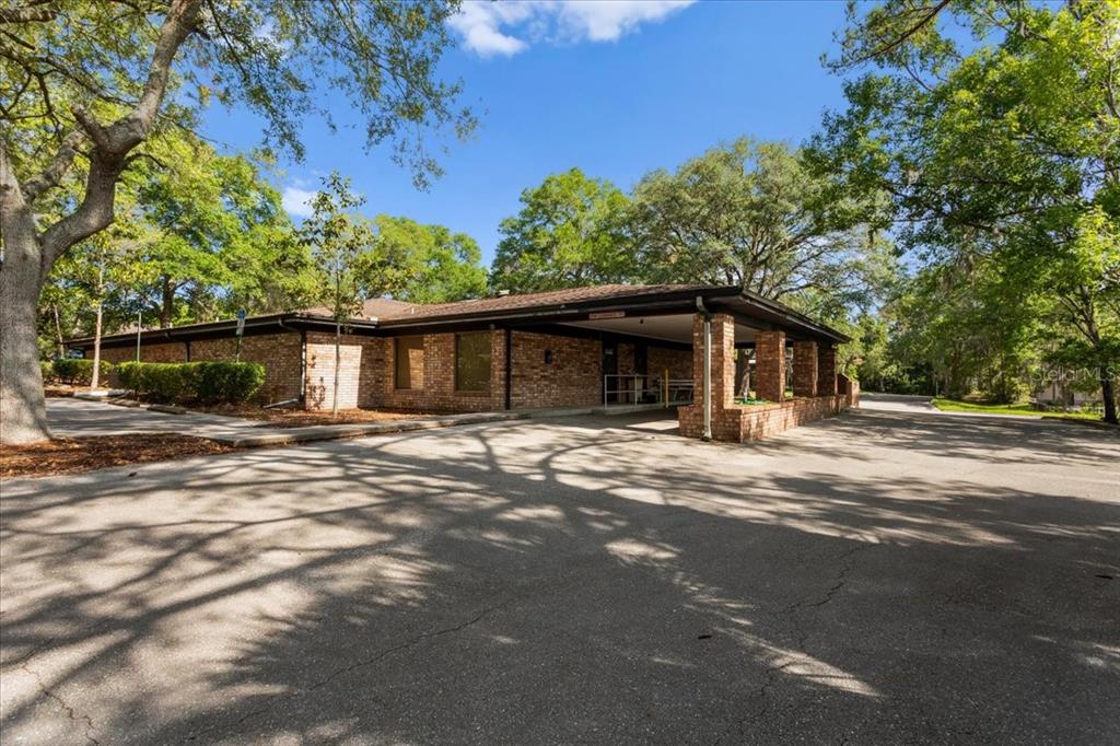A single-story brick building features a covered entrance with brick columns and a paved driveway — 7019 NW 11TH PLACE, GAINESVILLE, FL