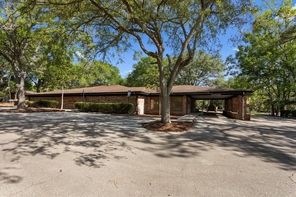 A single-story brick commercial building with a covered entrance and a large paved parking lot — 7019 NW 11TH PLACE, GAINESVILLE, FL