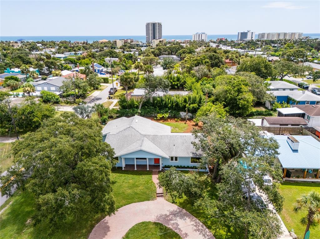 An aerial view shows a house with a gray roof, a driveway, and surrounding landscaping — 1460 N PENINSULA DRIVE, DAYTONA BEACH, FL
