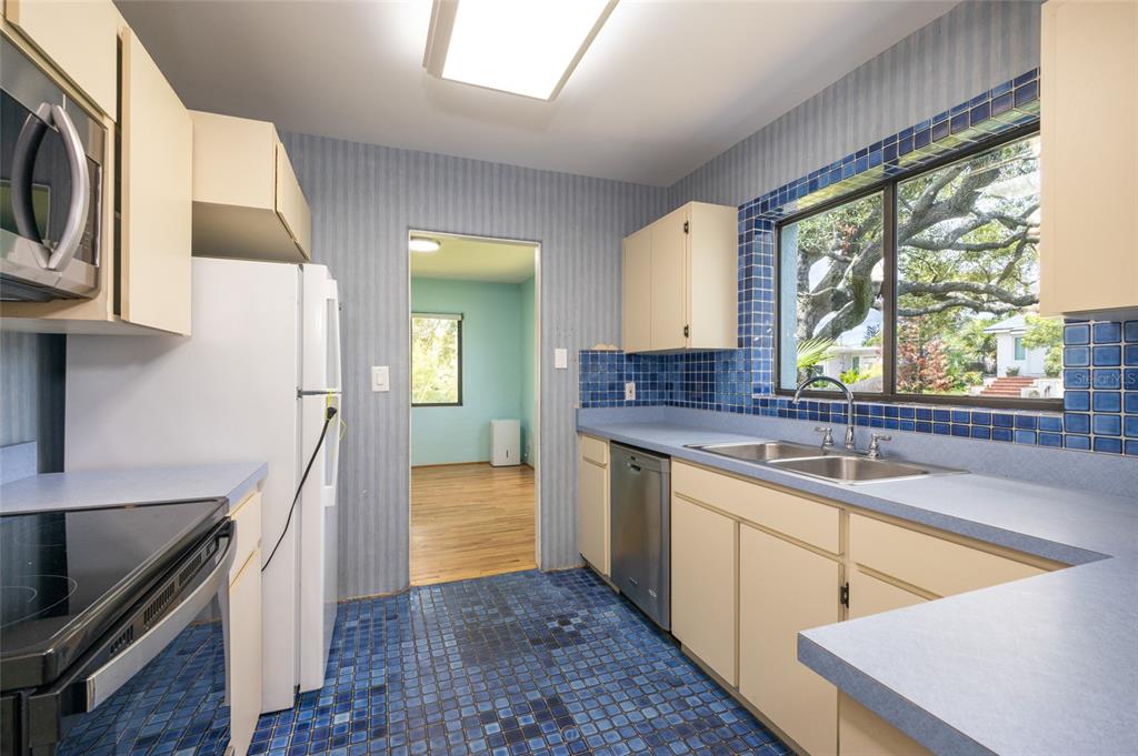 A light blue single-story house features a red front door and a brick paver driveway — 1460 N PENINSULA DRIVE, DAYTONA BEACH, FL