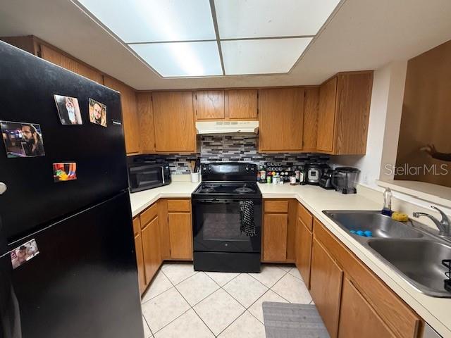 A kitchen features wood cabinets, black appliances, a double sink, and a tiled backsplash — 5627 GREATPINE LANE N, JACKSONVILLE, FL