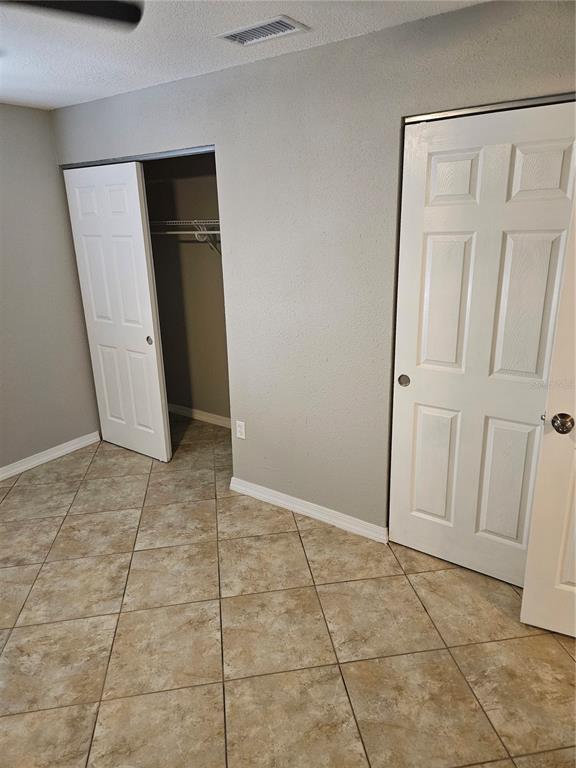 A room with tiled floors, gray walls, and two white doors leading to closets — 2744 HIDDEN LAKE BOULEVARD UNIT C, SARASOTA, FL