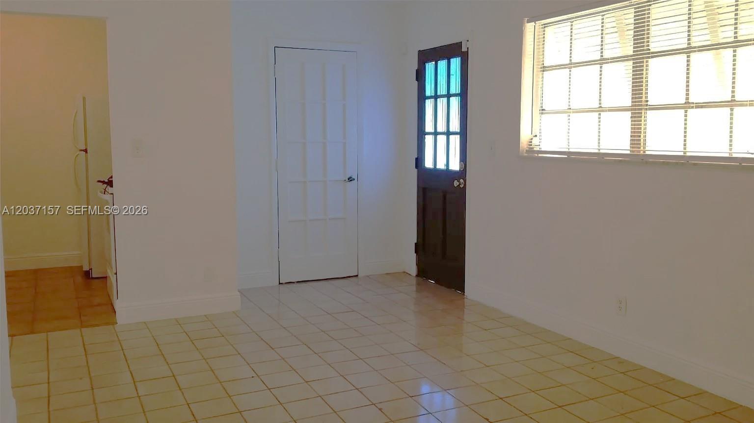 A room with light-colored tile flooring, a white door, and a dark-colored exterior door — 2010 NW 70th St, Miami FL 33147, MIAMI, FL