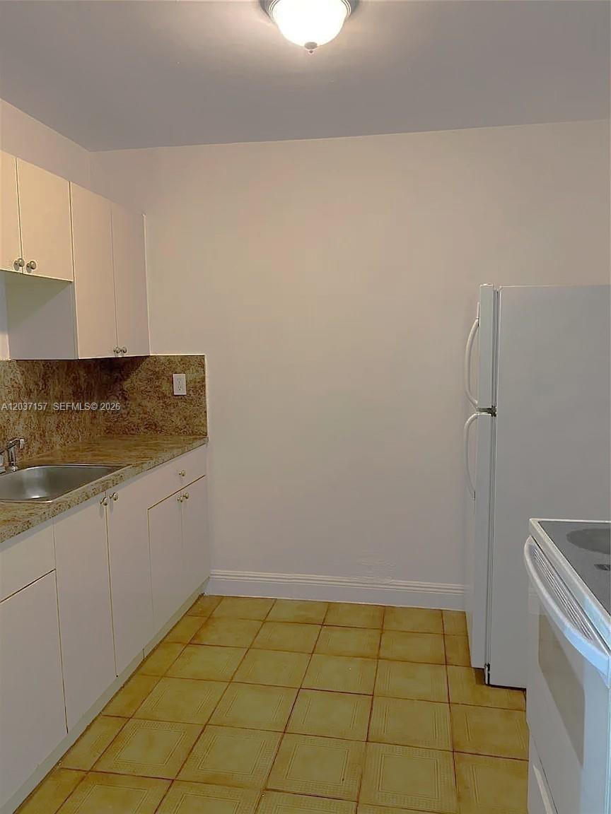 A kitchen features white cabinets, a granite countertop, a sink, and a white refrigerator — 2010 NW 70th St, Miami FL 33147, MIAMI, FL